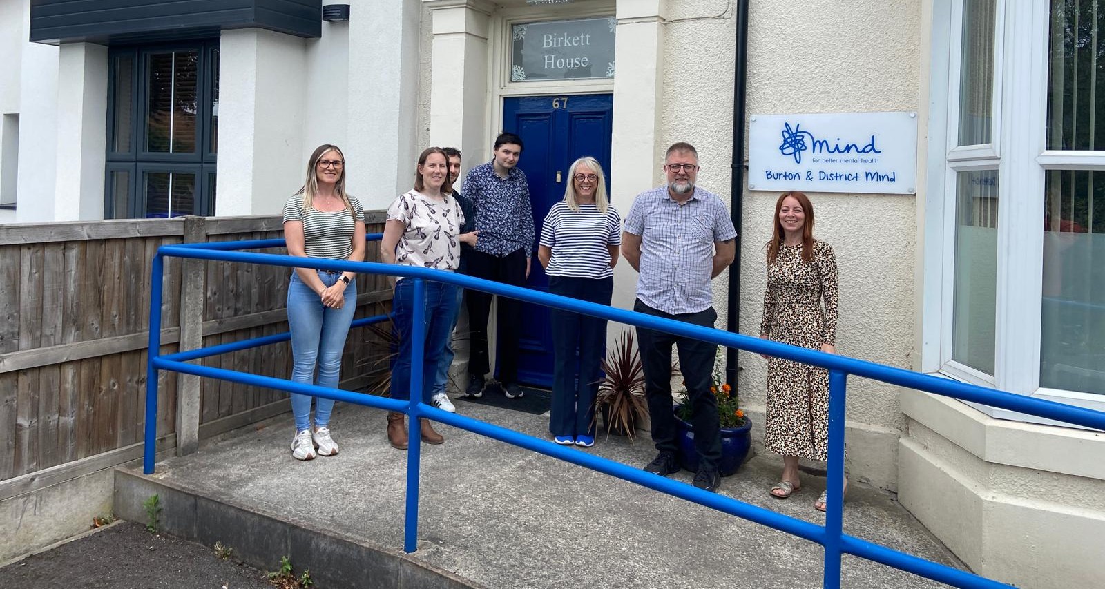photo showing staff of Burton on mind outside their office building 