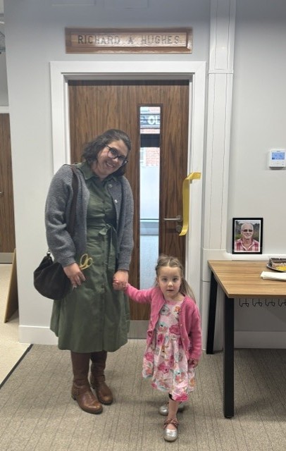 adult and small child standing by a door after cutting a ribbon