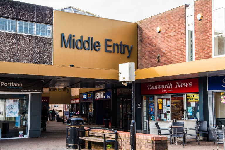 Shops and buildings with a golden bridge with the words 'Middle Entry' on it.