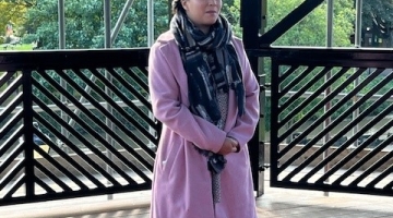 Cllr Nova Arkney standing inside the refurbished bandstand wearing a pink coat and scarf