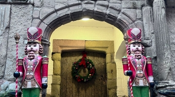 photo taken outside castle door to the Great Hall and porch, with a Christmas wreath and two nutcracker statues