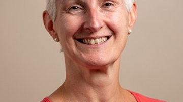 photo of a person with light short hair wearing an orange top