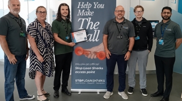 group of people standing by a poster, holding a certificate